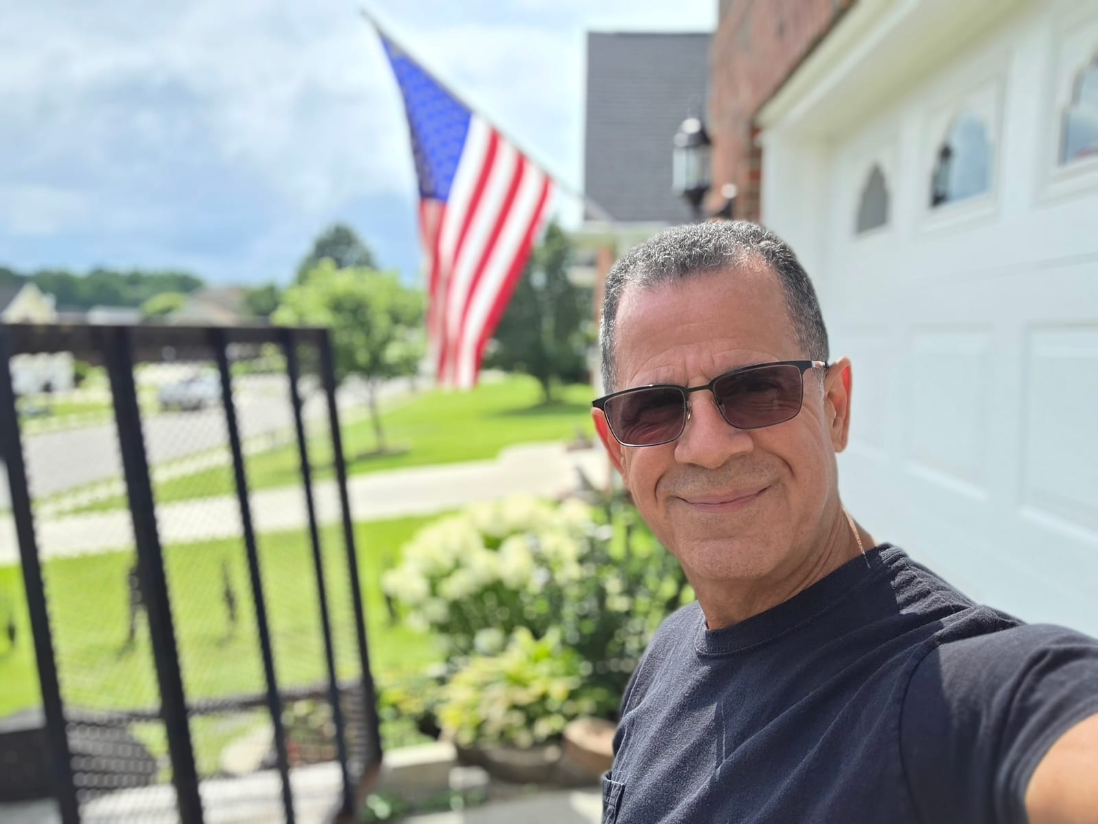 George Hinestrosa en casa, junto a la bandera estadounidense